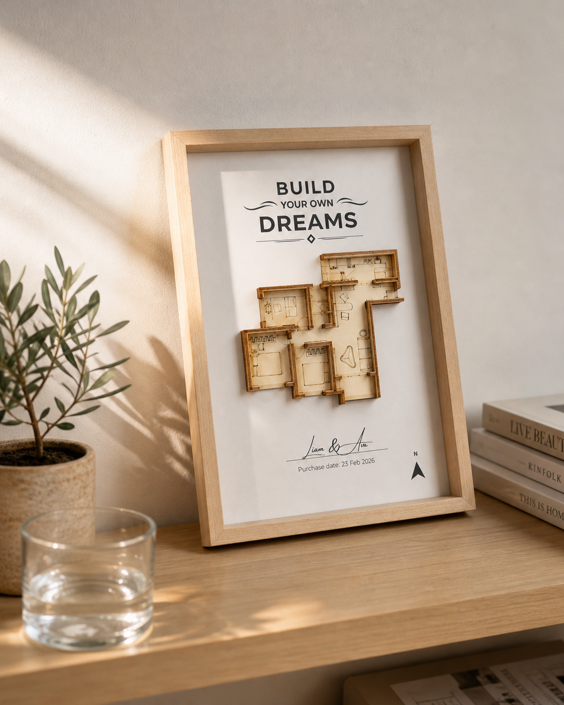 Framed motivational poster with wooden cutouts on a shelf with a plant and books in the background